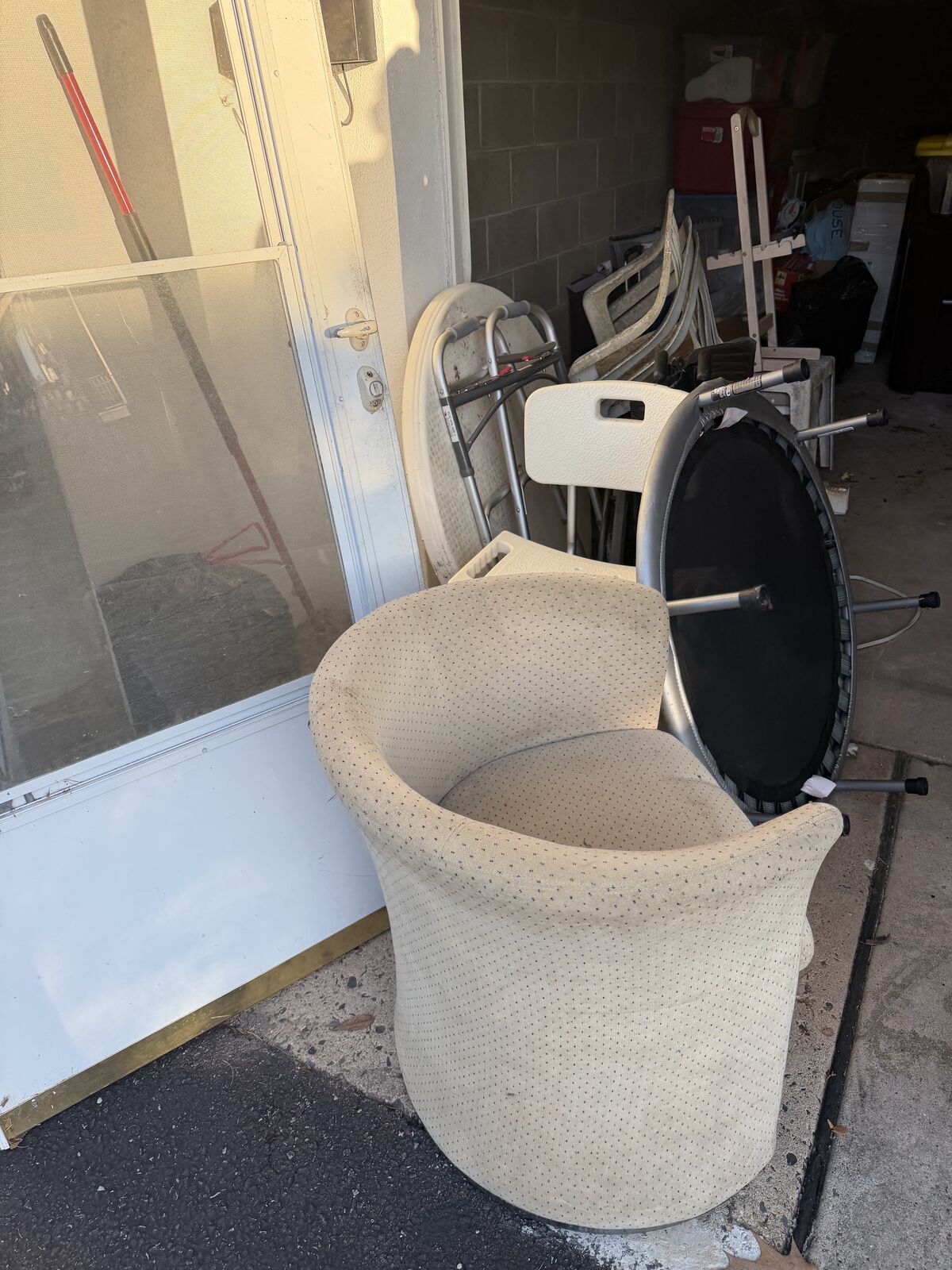 Chair, screen door, mini trampoline, and other household items gathered for removal